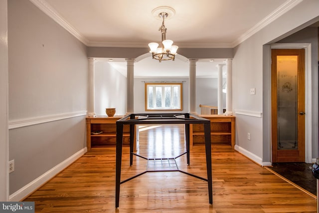 bedroom with hardwood / wood-style floors, a notable chandelier, ornamental molding, and ornate columns