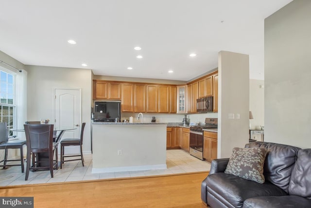 kitchen with sink, light stone counters, light hardwood / wood-style flooring, and black appliances