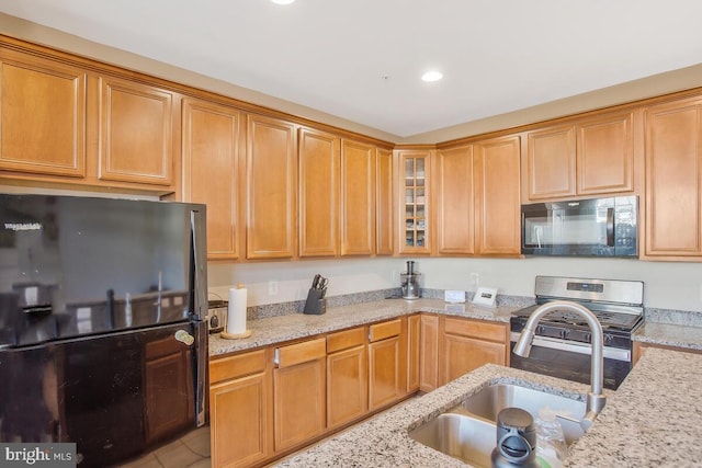 kitchen with light stone countertops, sink, and black appliances