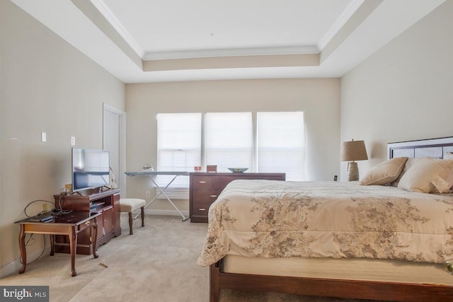 bedroom with light colored carpet, ornamental molding, and a tray ceiling