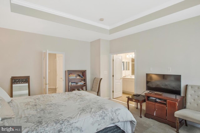 carpeted bedroom featuring a tray ceiling and connected bathroom