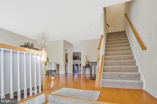 stairs featuring a chandelier and wood-type flooring