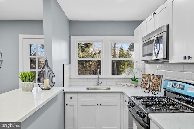 kitchen featuring white cabinets, stainless steel appliances, plenty of natural light, and sink