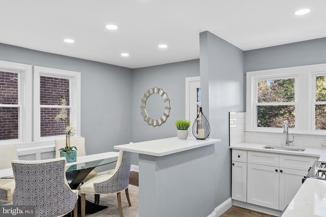 kitchen featuring kitchen peninsula, hardwood / wood-style floors, white cabinetry, and sink