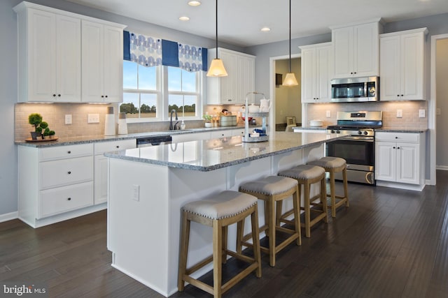 kitchen featuring white cabinets, a center island, stainless steel appliances, and dark hardwood / wood-style floors