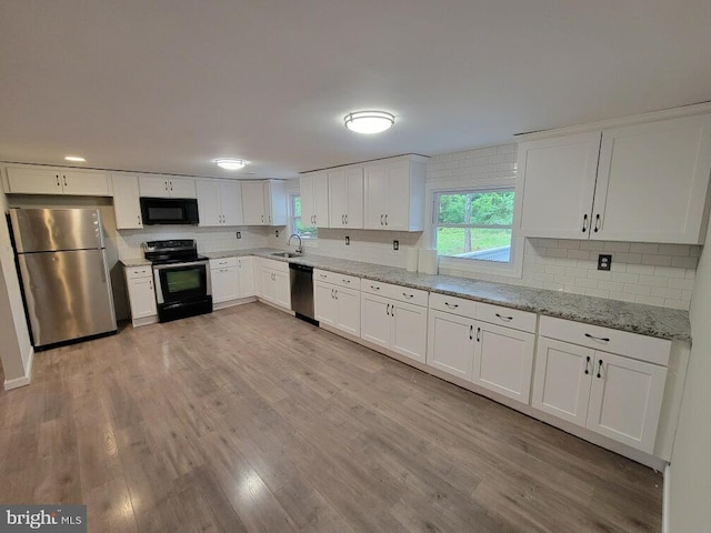 kitchen with black appliances, sink, light stone countertops, light hardwood / wood-style floors, and white cabinetry