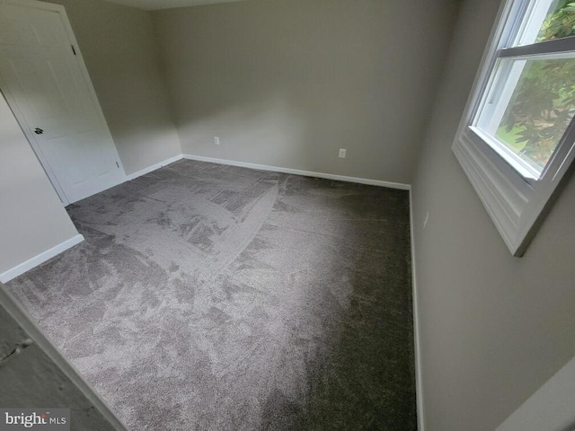 unfurnished room featuring dark colored carpet