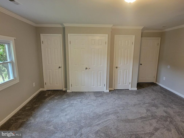 unfurnished bedroom with two closets, dark carpet, and crown molding