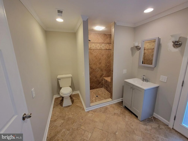 bathroom with toilet, a tile shower, crown molding, and vanity