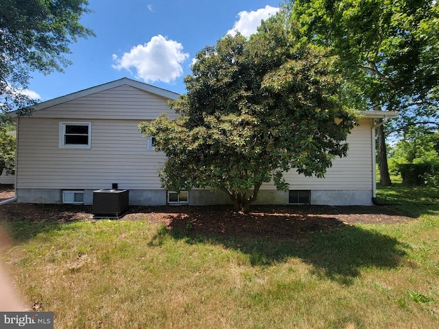 view of side of home featuring central AC and a lawn