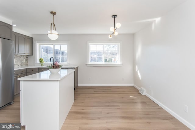 kitchen with stainless steel refrigerator, plenty of natural light, a center island, and light wood-type flooring