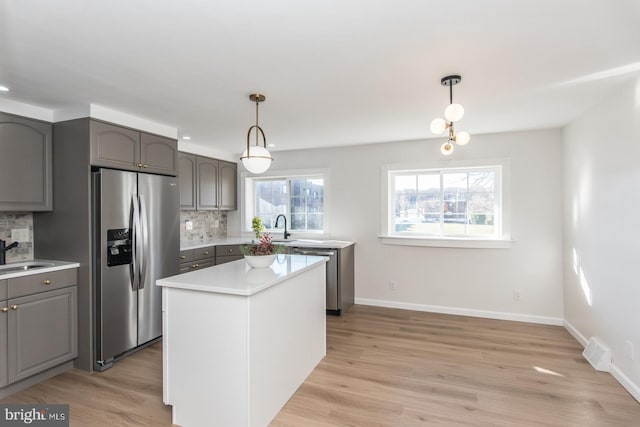 kitchen featuring pendant lighting, a center island, light hardwood / wood-style flooring, appliances with stainless steel finishes, and tasteful backsplash