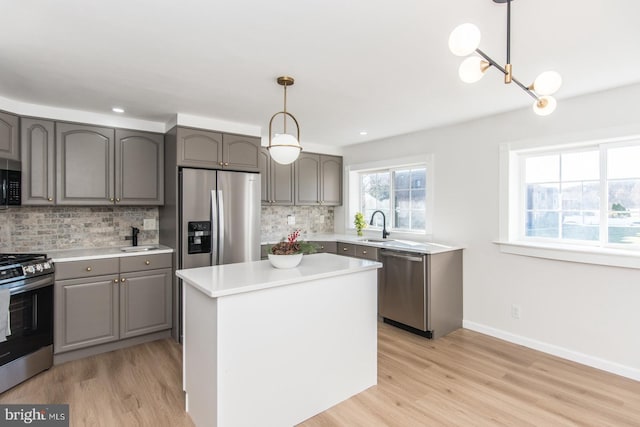 kitchen featuring a center island, hanging light fixtures, stainless steel appliances, light hardwood / wood-style floors, and decorative backsplash