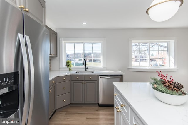 kitchen featuring gray cabinetry, sink, stainless steel appliances, and light wood-type flooring