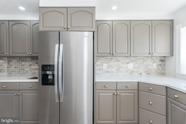 kitchen with gray cabinetry, stainless steel fridge, and decorative backsplash