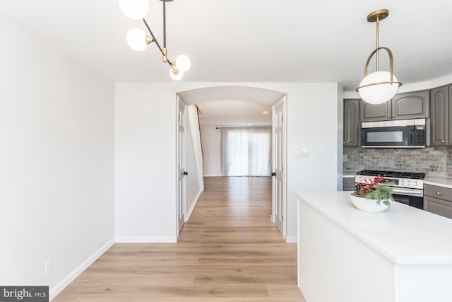 kitchen featuring backsplash, gray cabinets, light hardwood / wood-style floors, and appliances with stainless steel finishes