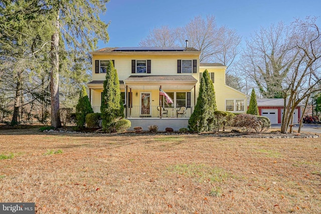 view of front of property with covered porch, solar panels, and a front yard