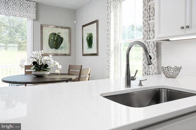 kitchen with white cabinets, backsplash, and sink