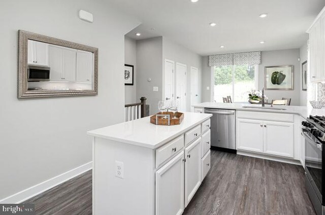 kitchen with sink, dark hardwood / wood-style floors, appliances with stainless steel finishes, a kitchen island, and white cabinetry