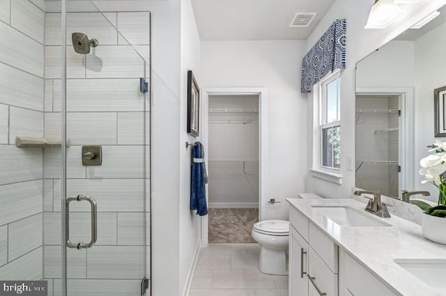 bathroom with tile patterned flooring, vanity, toilet, and a shower with door