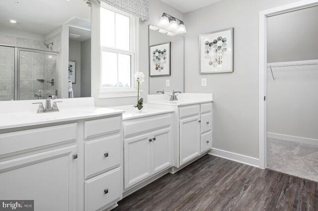 bathroom with hardwood / wood-style flooring, vanity, and a shower with door