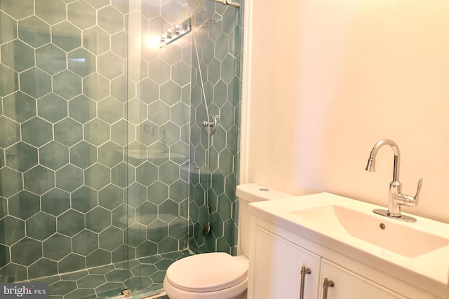 bathroom with vanity, toilet, and tiled shower