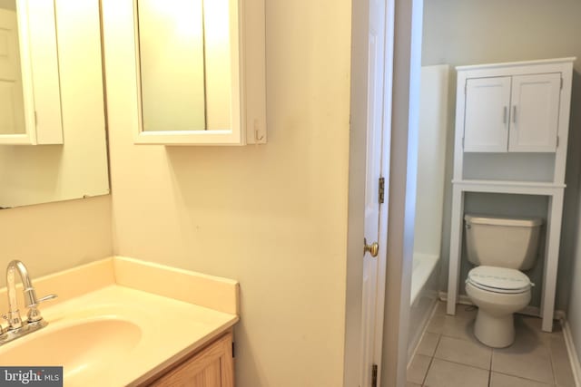 bathroom with a washtub, toilet, vanity, and tile patterned flooring