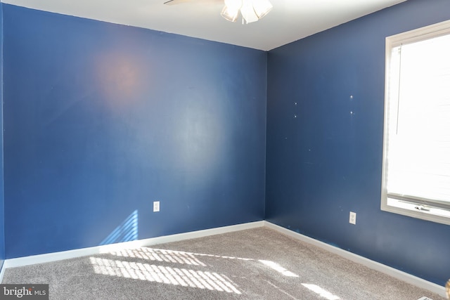 carpeted empty room with ceiling fan and a wealth of natural light