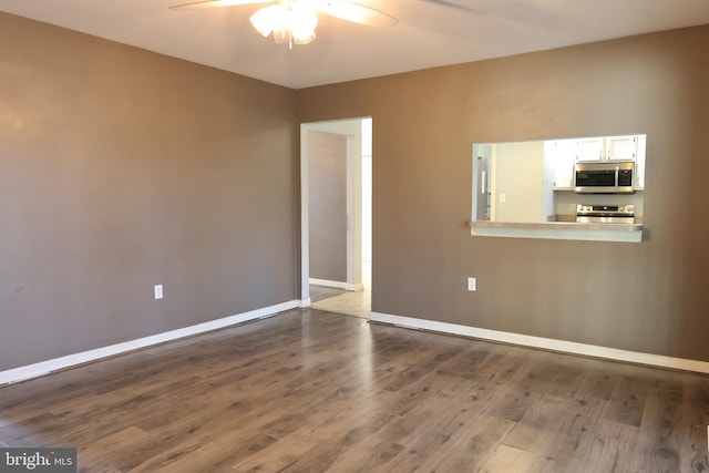 empty room with ceiling fan and dark hardwood / wood-style flooring