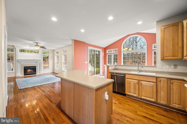 kitchen featuring dishwasher, a center island, sink, vaulted ceiling, and light hardwood / wood-style floors