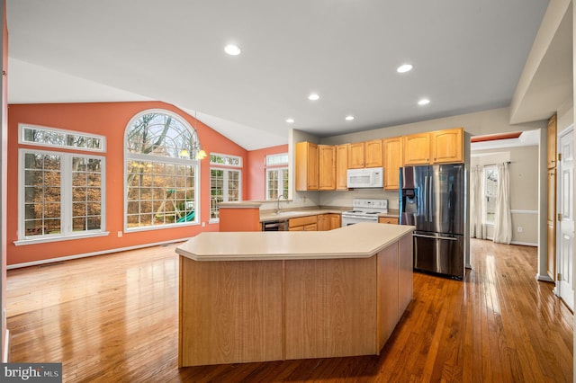 kitchen featuring a center island, lofted ceiling, light hardwood / wood-style flooring, appliances with stainless steel finishes, and kitchen peninsula