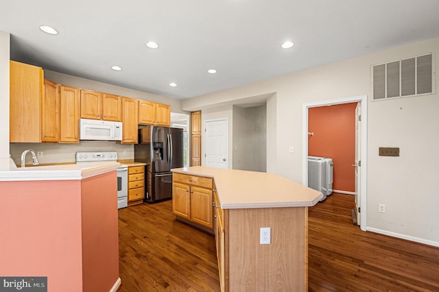 kitchen with a center island, sink, dark wood-type flooring, white appliances, and washer / dryer