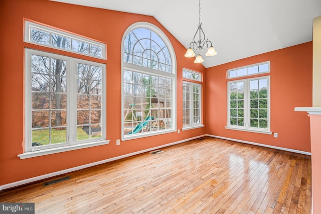 unfurnished sunroom with lofted ceiling, a wealth of natural light, and an inviting chandelier