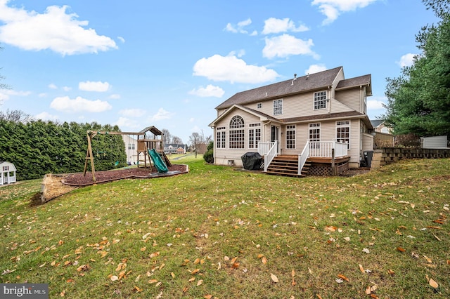 rear view of property featuring a playground, a lawn, and a wooden deck