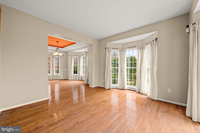 spare room with a chandelier and light wood-type flooring