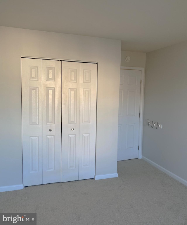 unfurnished bedroom with a closet and light colored carpet