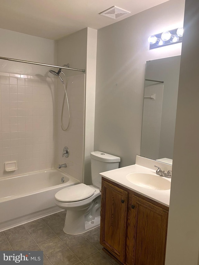 full bathroom with tile patterned flooring, vanity, tiled shower / bath combo, and toilet