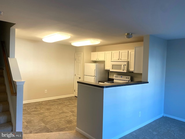 kitchen with kitchen peninsula, white appliances, and white cabinetry