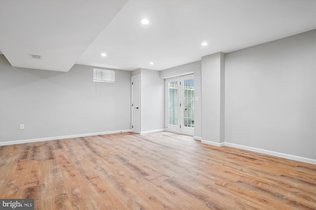 basement with light hardwood / wood-style flooring and french doors