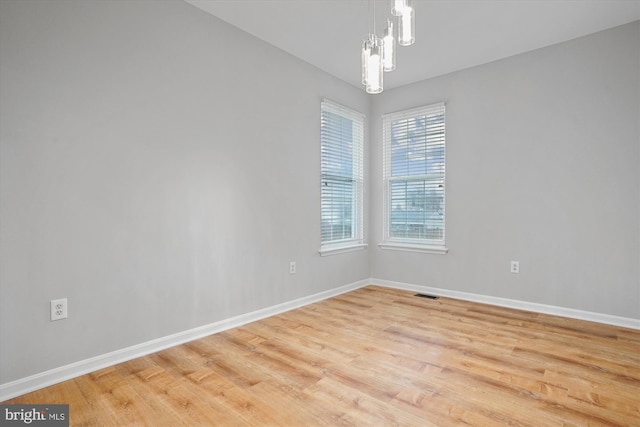 empty room featuring light hardwood / wood-style floors and an inviting chandelier