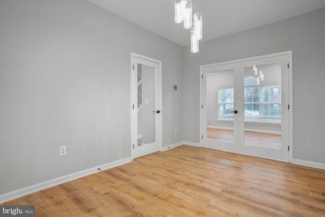 spare room featuring light wood-type flooring and an inviting chandelier