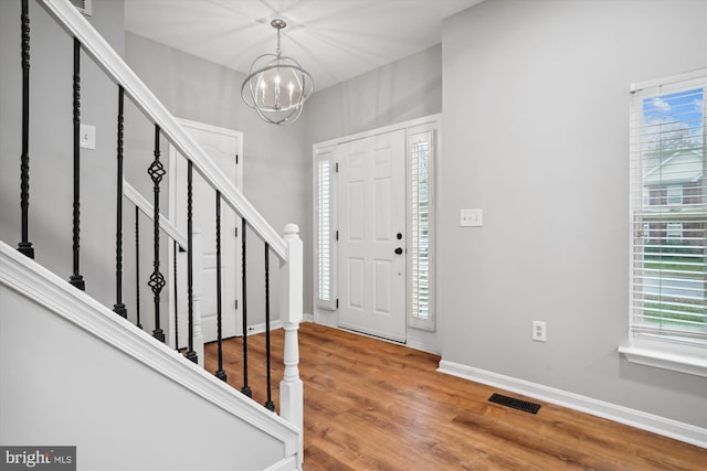 foyer entrance with hardwood / wood-style floors and a chandelier