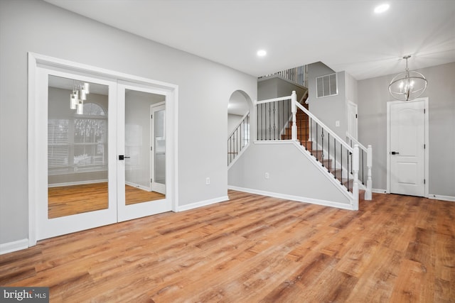 unfurnished living room featuring hardwood / wood-style flooring, a notable chandelier, and french doors