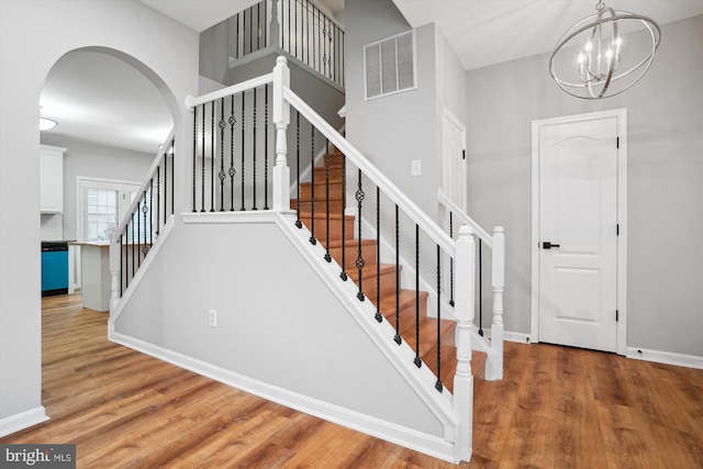 staircase with a chandelier and hardwood / wood-style flooring