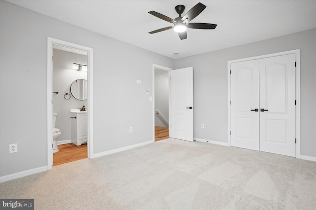 unfurnished bedroom with ensuite bathroom, ceiling fan, light colored carpet, and a closet