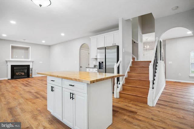 kitchen featuring white cabinets, light hardwood / wood-style floors, a kitchen island, and butcher block counters