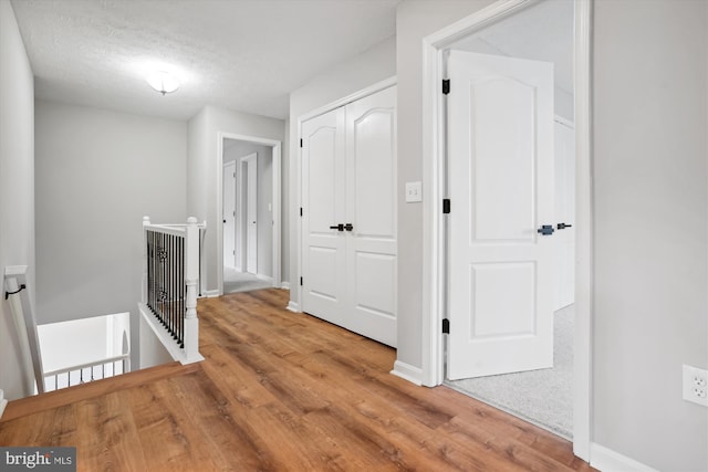 hall with hardwood / wood-style floors and a textured ceiling