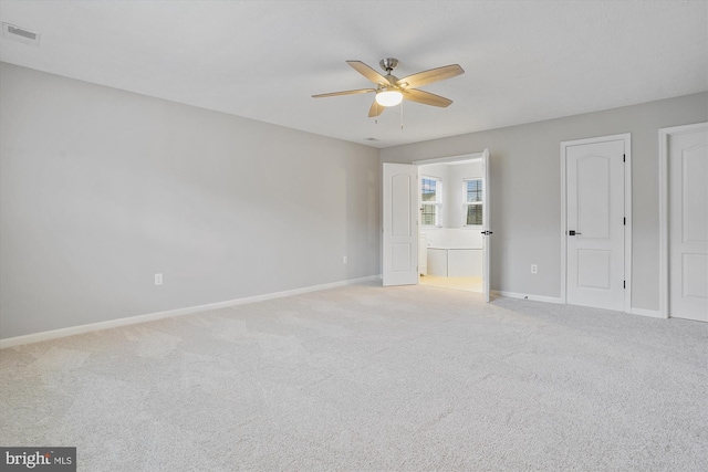 unfurnished bedroom with ceiling fan, light colored carpet, and connected bathroom