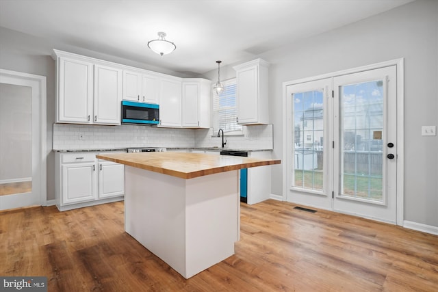 kitchen featuring white cabinetry, hanging light fixtures, and wood counters