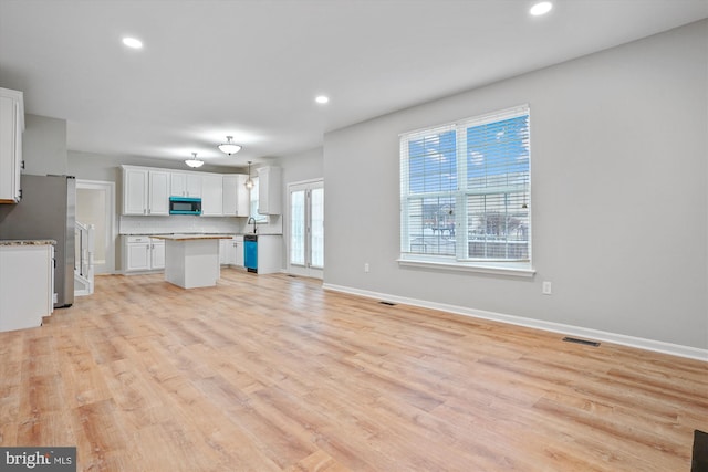 kitchen with a kitchen island, white cabinets, light hardwood / wood-style flooring, and appliances with stainless steel finishes